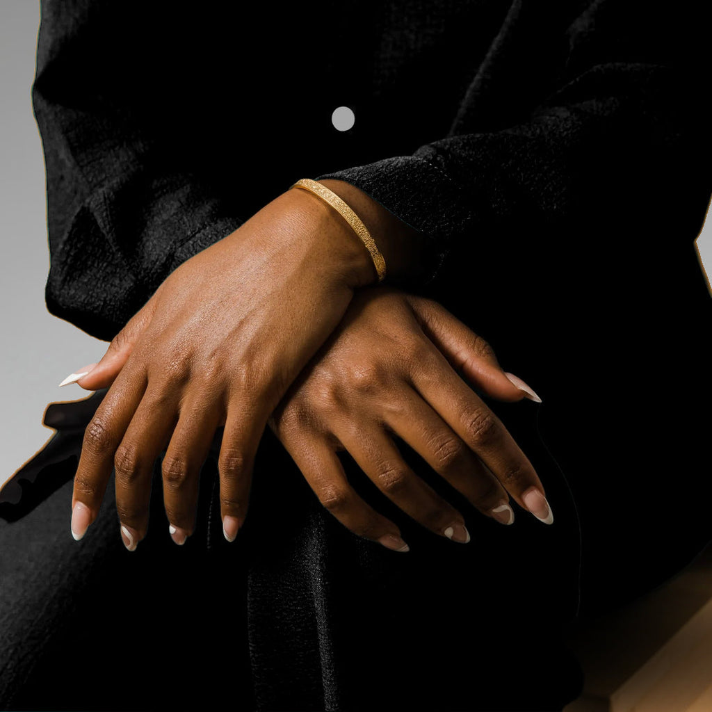 Close-up of two hands resting on a black surface with a neutral background Wearing the Cairo ayatul kursi bracelet